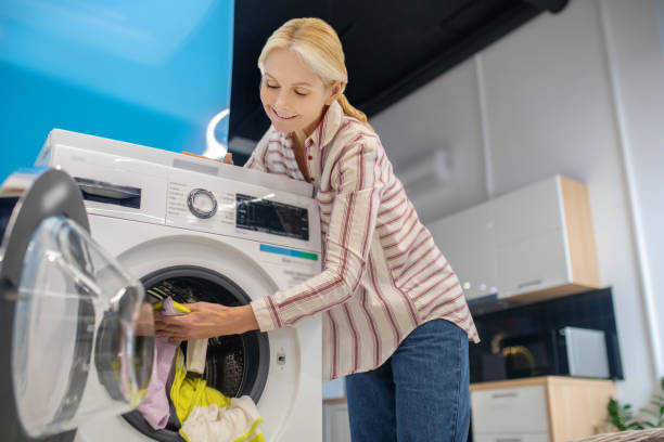istock Blonde woman taking clothes from washing machine 1290548075
