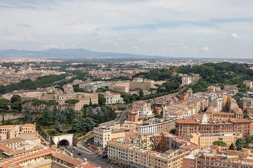 Panoramic view on city of Rome from Papal Basilica of St. Peter (St. Peter's Basilica). Summer day, people walk on street and cars on road