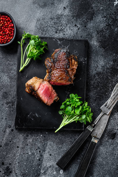 istock Grilled Striploin or new york steak. Black background. Top view 1290552270