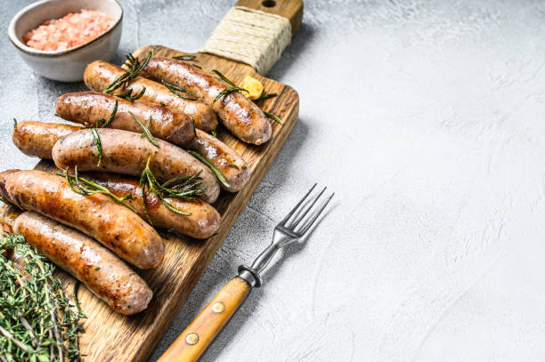istock Grilled mix sausages with herbs on a cutting board. White background. Top view. Copy space 1290554804