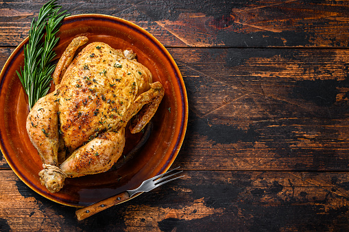 Delicious baked chicken on wooden table.  Dark background. Top view. Copy space.
