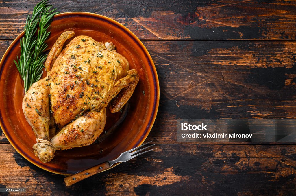 Delicious baked chicken on wooden table.  Dark background. Top view. Copy space Delicious baked chicken on wooden table.  Dark background. Top view. Copy space. Roast Chicken Stock Photo