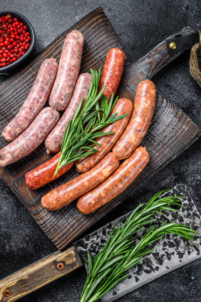 istock Assorted raw chorizo sausages on a wooden cutting board. Black background. Top view 1290555754