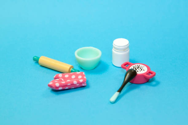flat lay image of plastic toy tableware with kitchen oven mitt glove on pastel blue background