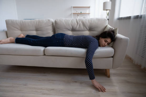 istock Tired exhausted Asian woman sleeping on couch at home 1290561501