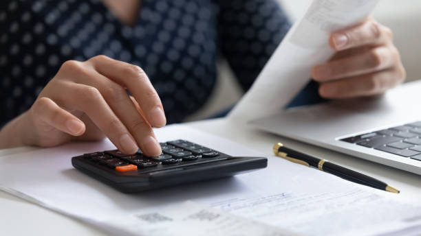 istock Close up woman calculating finances, using calculator and laptop 1290561526