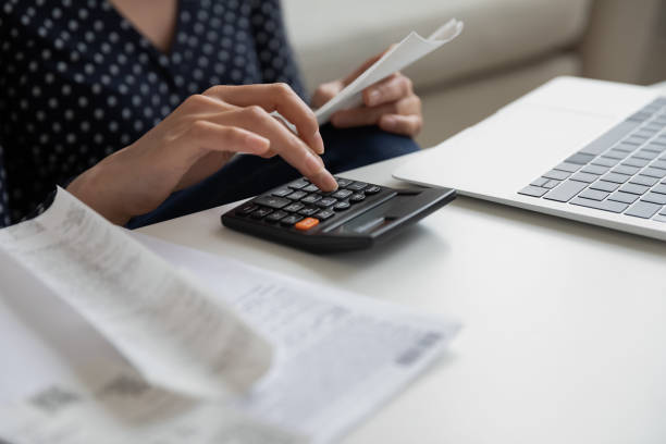 istock Close up woman calculating bills, using calculator, holding receipt 1290561534