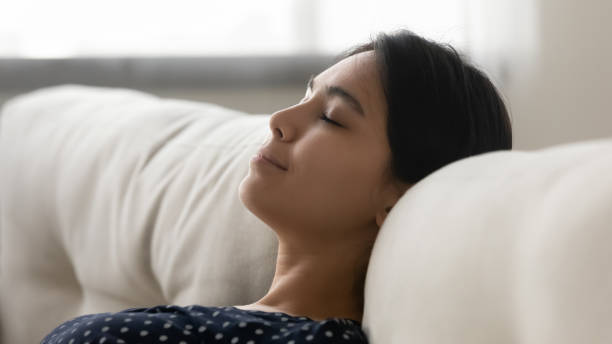 istock Close up tranquil calm Asian young woman resting on sofa 1290561550