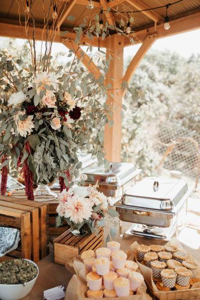 istock Rustic backyard wedding - reception tables with golden plates and chairs, dahlias, peonies and eucalyptus leaves and jute rope napkin rings. 1290561662