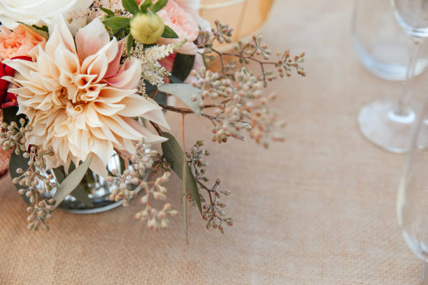 istock Rustic backyard wedding - reception tables with golden plates and chairs, dahlias, peonies and eucalyptus leaves and jute rope napkin rings. 1290561891