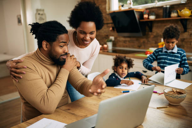 istock Happy black couple talking while man is working on laptop at home. 1290562420