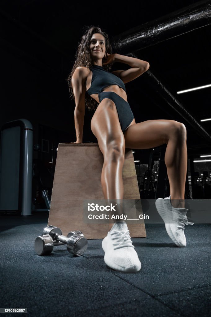 Tall athletic woman smiles and poses in the gym with a metal