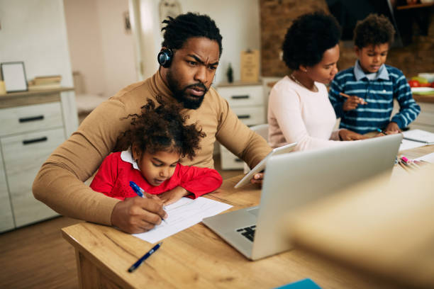 istock Multi-tasking black father working at home while daughter is sitting on his lap. 1290562637