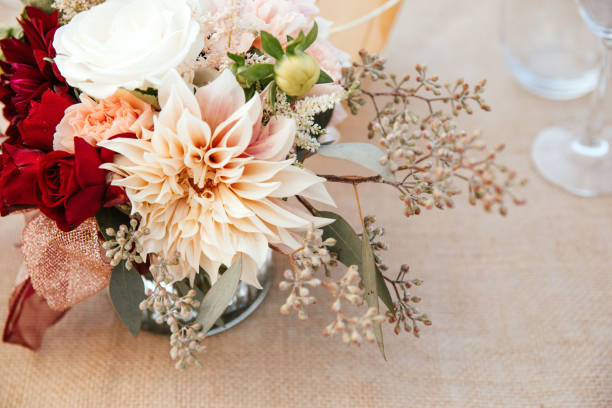 istock Rustic backyard wedding - reception tables with golden plates and chairs, dahlias, peonies and eucalyptus leaves and jute rope napkin rings. 1290562668