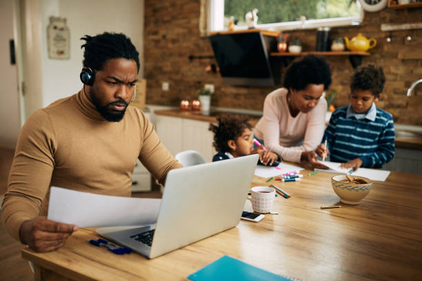 istock African American working father using laptop while mother is homeschooling their children. 1290563229