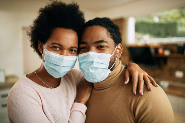 istock Embraced black couple wearing protective face masks at home. 1290563260