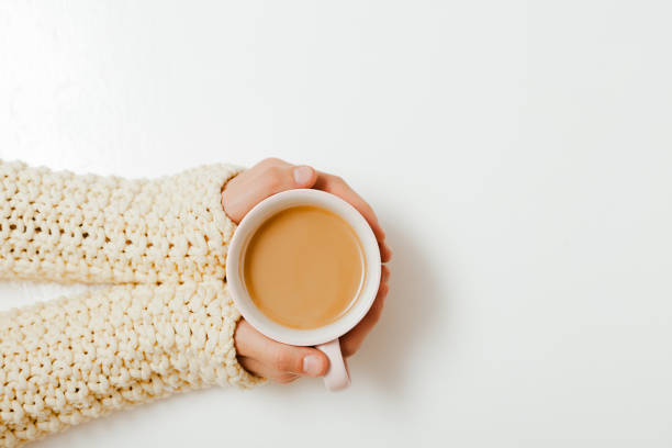 istock Female hands holding cups of coffee on white table background 1290564238