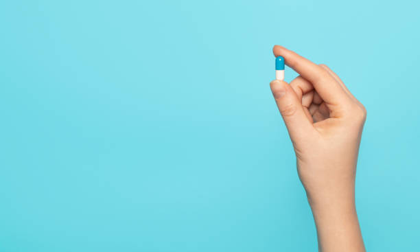 istock Tablet capsule in hand on a blue background, top view. 1290567273
