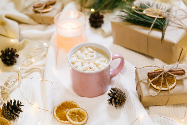 istock Warm and cozy home atmosphere preparing for holidays and celebration. Christmas composition. Hot chocolate, cinnamon, marshmallow, knitted blanket and pine cones. Flat lay, top view. 1290567416
