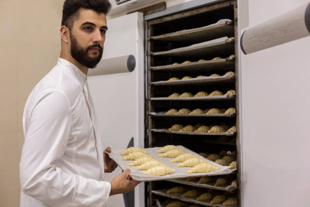 istock Pastry chef with tray of croissant 1290567703