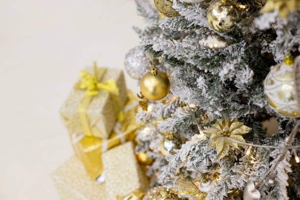 istock Decorated Christmas tree with golden patchwork ornament artificial gold and white balls and big gift presents for new year isolated on white background.fir branches with christmas ornaments. 1290569824