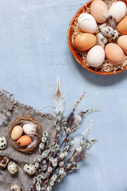 istock Chicken  and  Quail eggs on a plate with willow on a light gray background. Pattern with straw and feathers. 1290571611