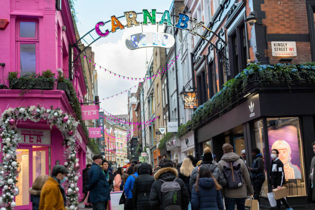 Crowded streets of Carnaby after lockdown London, UK - December 05, 2020: Crowd of people on the busy shopping streets of Carnaby in London at dusk. soho billboard stock pictures, royalty-free photos & images