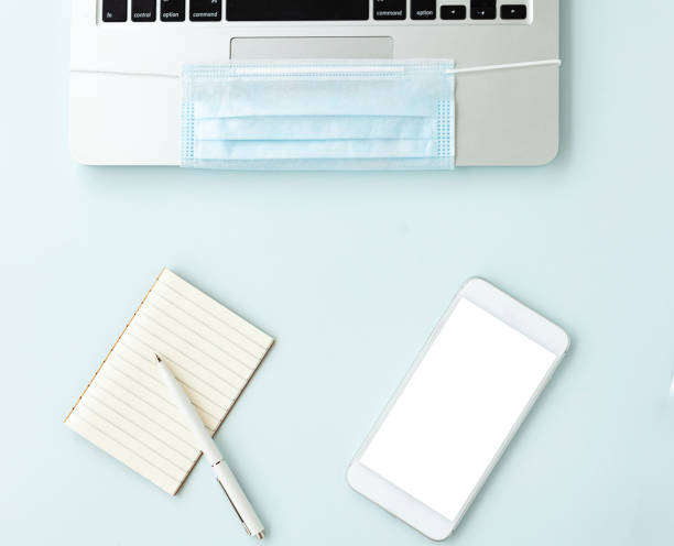 istock Coronavirus Covid-19 Prevention. Remote work or learning in quarantine. Laptop and antiviral medical mask, phone Notepad and pen they lie next to each other. Remote work, office work, freelance 1290573814