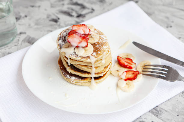 istock A stack of pancakes with fresh strawberries on a white plate on a light background. A white flower in a glass vase stands next to the Breakfast. 1290573969