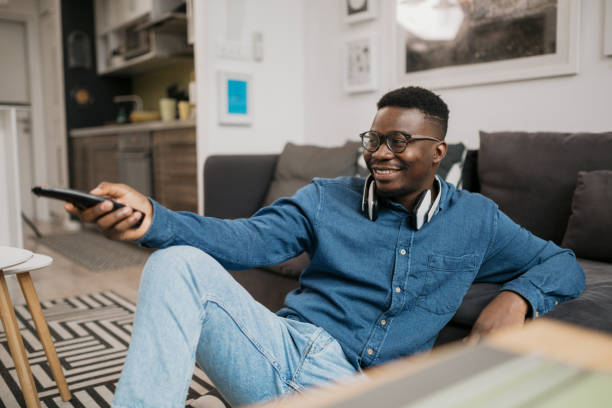 istock Young African American man watching television at home 1290574890