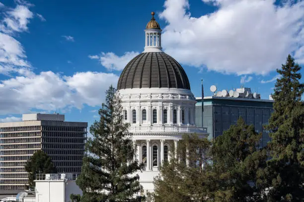 California State Capitol building dome in Sacramento with cloudy sky.