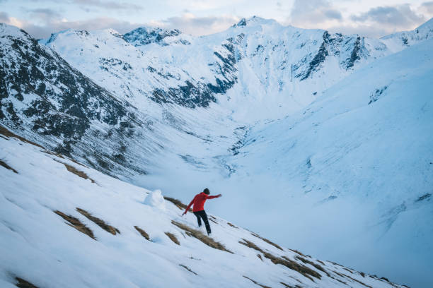 istock Young man trail runs down snowy mountain slope in the morning 1290576407