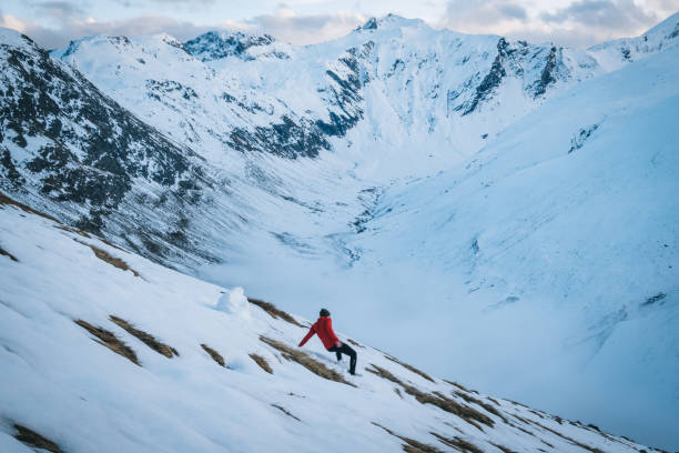 istock Young man trail runs down snowy mountain slope in the morning 1290576410