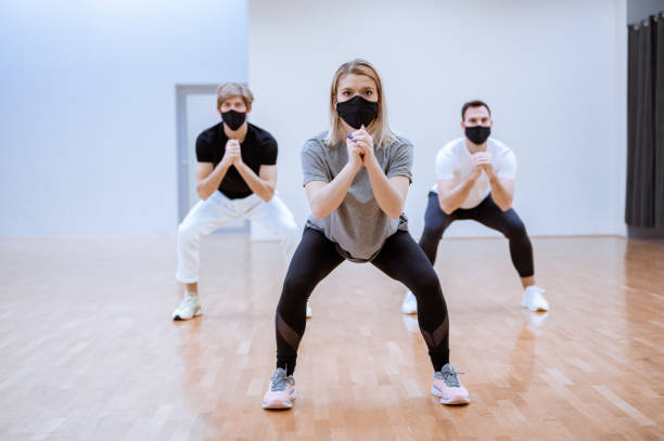 屋内で運動する顔保護マスクを持つ人々の小さなグループ - health club social gathering exercising sport ストックフォトと画像