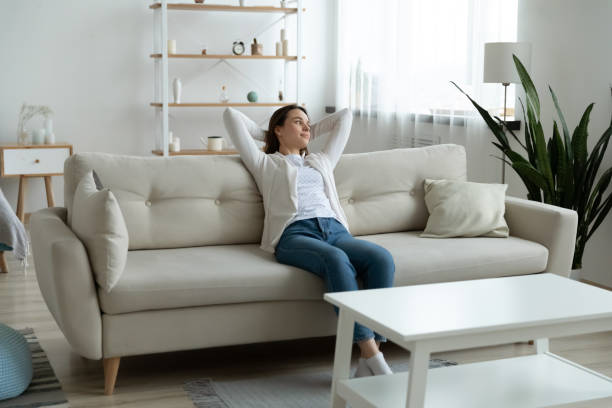 istock Happy young woman relax on couch at home 1290577424