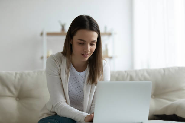istock Young woman look at laptop screen browsing web at home 1290577489