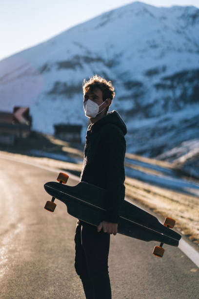 istock Longboarder wearing protective face mask relaxes on mountain road 1290577701