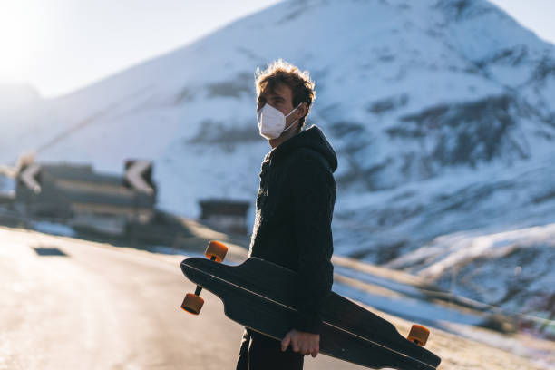istock Longboarder wearing protective face mask relaxes on mountain road 1290578801