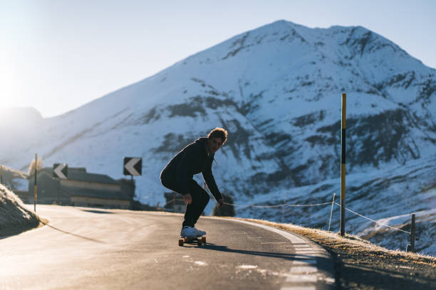 istock Young man longboards down mountain road in the morning 1290578802