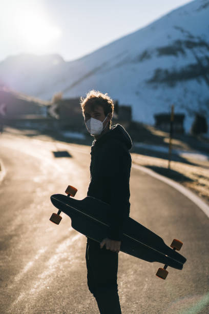istock Longboarder wearing protective face mask relaxes on mountain road 1290578846