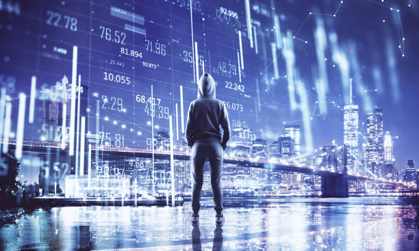 istock Hacker in hoodie looking on night Brooklyn bridge with digital stock chart. 1290582666