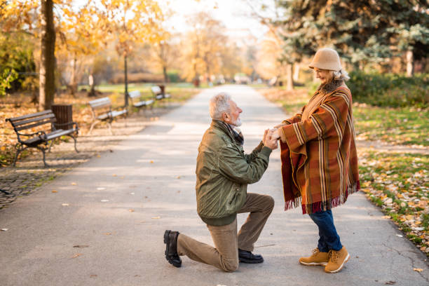 Romantic senior man proposing to his lady in the park.