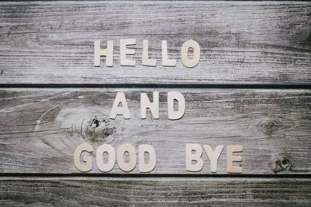 Hello and good bye wooden letters written no a striped wooden background close up still