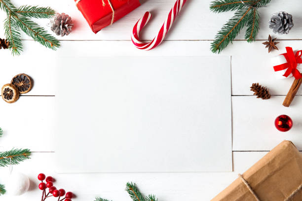 istock Beautiful Christmas composition on wooden white background. Empty card with Christmas present boxes, snowy fir branches, conifer cones, caramel stick, gift. New Year. Top view, copy space. 1290584274