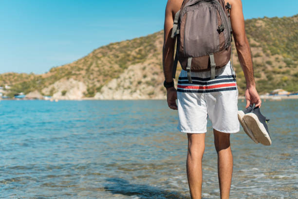 istock Young man walking barefoot on a deserted beach 1290597094