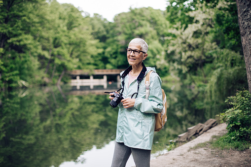 Senior woman enjoying her adventure in the nature and photographing.