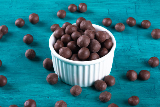 istock Chocolate balls in white bowl on blue background. 1290598855