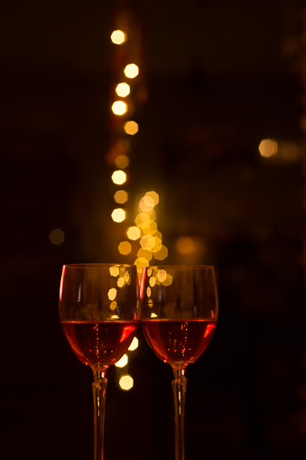 Two glasses of red wine against the backdrop of lights on a festive night