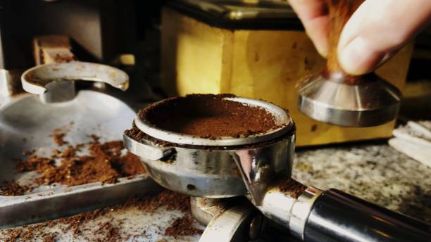 istock Barista Tamping Ground Coffee to make Espresso 1290599073