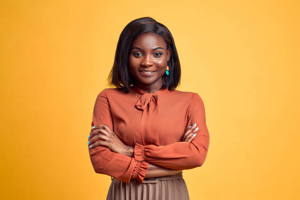 Advertising concept. Confident and smiling young african american woman crossed hands on chest, looking at camera and standing on yellow copy space background. Advertising concept. Confident and smiling young african american woman crossed hands on chest, looking at camera and standing on yellow copy space background. 25 29 years stock pictures, royalty-free photos & images